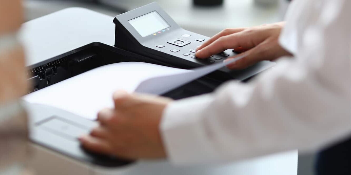 Woman in office prints documents on printer. Scanning documents at workplace concept